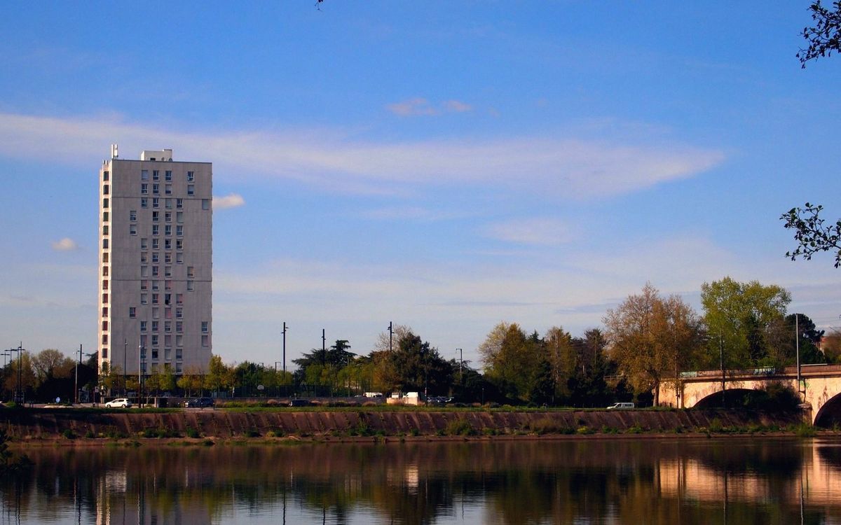 The illuminated LU tower at dusk above the rooftops of Nantes